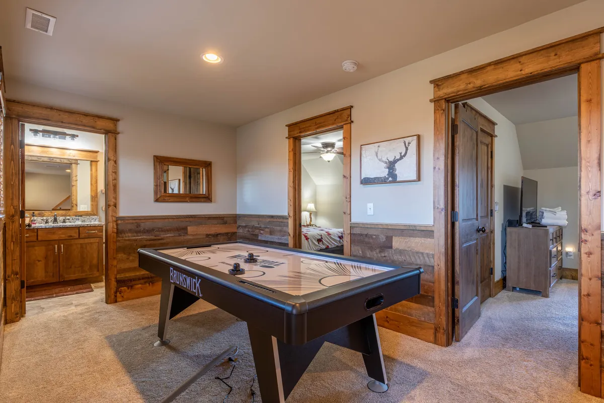 A lively interior view featuring an air hockey table, wooden doors, and framed artwork. The space captures the energy of game nights and shared laughter, making it clear that indoor entertainment is a big part of the family fun story at the cabin.